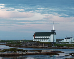 Historic St. Luke&rsquo;s Anglican Church, Newtown, Newfoundland and Labrador, Canada. A white located on a rocky shoreline with clouds and late evening light.