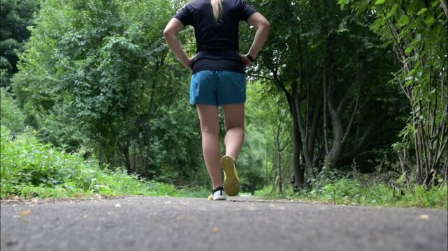 A young woman is resting after a run in the park. Charming athletic woman is resting after exercising.