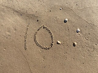 On the beach in the sand is carved the number 10