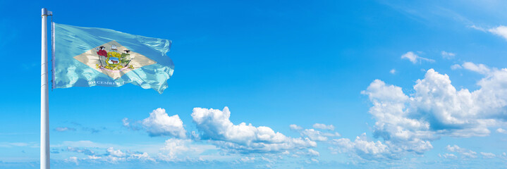 Fototapeta na wymiar Delaware - state of USA, flag waving on a blue sky in beautiful clouds - Horizontal banner 