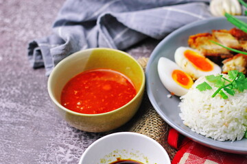 Thai dish '' Khao mu daeng '' or red sauce pork stew with rice and spring onions served in a gray plate on the black table in the restuarant