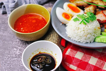 Thai dish '' Khao mu daeng '' or red sauce pork stew with rice and spring onions served in a gray plate on the black table in the restuarant