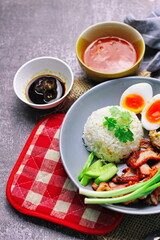 Thai dish '' Khao mu daeng '' or red sauce pork stew with rice and spring onions served in a gray plate on the black table in the restuarant