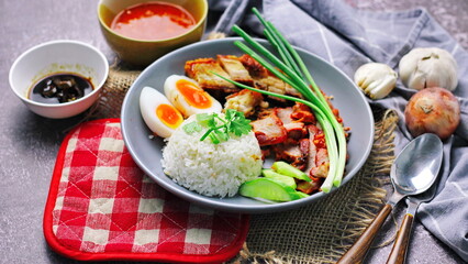 Thai dish '' Khao mu daeng '' or red sauce pork stew with rice and spring onions served in a gray plate on the black table in the restuarant