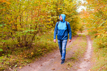 Obraz premium A middle age male hiking with a backpack.Man walks along the autumn forest path way.A healthy lifestyle in nature.