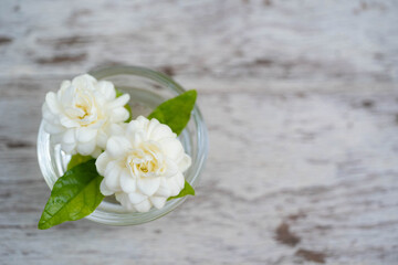 Fresh white Jasmine flower in clear mini cup on old wooden background