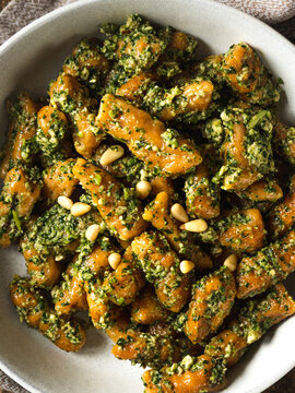 Macro shot of the homemade vegan sweet potato gnocchi with pesto sauce with wild garlic and pine nuts on top, top view 