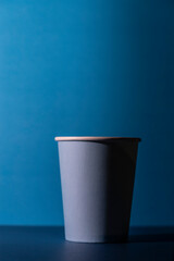 Single light blue paper cup with white rim on navy blue background.