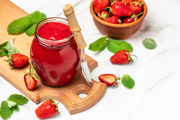 Jar of strawberry jam and fresh berries on wooden board white background. Long banner format