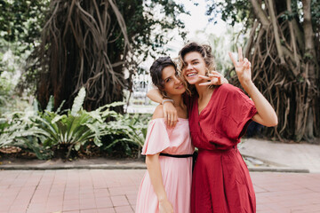 Romantic ladies in summer attire posing on exotic background. Outdoor photo of winsome caucasian girls travelling in spring.