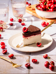 Cheesecake with chocolate ganache and cherries layer, a slice of cake on the table