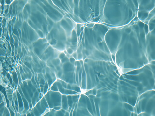 Bluewater waves on the surface ripples blurred. Defocus blurred transparent blue colored clear calm water surface texture with splash and bubbles. Water waves with shining pattern texture background.