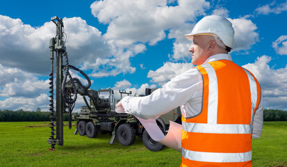 Drilling of wells. Man builder in orange vest back to camera. Builder man controls drilling of...