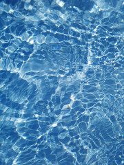 Defocus blurred transparent blue colored clear calm water surface texture with splash, bubble. Shining blue water ripple background. Surface of water in swimming pool. Blue bubble water shining.