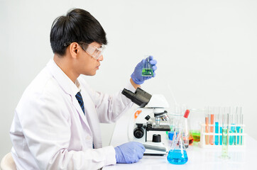 young attractive asian scientist working in chemical laboratory,doing chemistry experiments with microscope