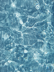 Defocus blurred transparent blue colored clear calm water surface texture with splash, bubble. Shining blue water ripple background. Surface of water in swimming pool. Blue bubble water shining.