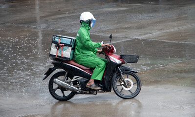 Obraz na płótnie Canvas Man with a delivery box on a motorcycle ride in the rain