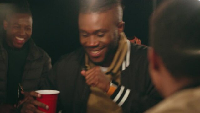 Party, friends and dance with a black man having fun, playing and drinking outside with a friend group. Happy, laughing and joking with a young male dancing at a celebration event in the night