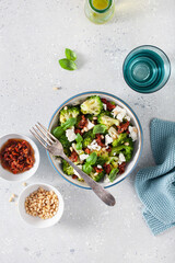 healthy broccoli salad with feta cheese sun dried tomatoes pine nuts. vegetarian low carb keto diet