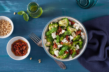 healthy broccoli salad with feta cheese sun dried tomatoes pine nuts. vegetarian low carb keto diet