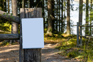 Close up of empty white sign on a wooden fence post in the woods