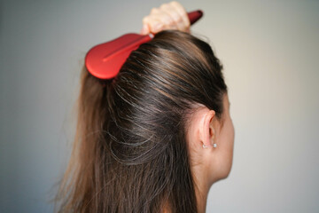 Naklejka premium A woman combs her hair. Gray hairs on the head of a young girl. Long gray hair. The initial stage of gray hair. The problem of gray hair in women.