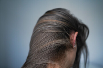 Gray hairs on the head of a young girl. Long gray hair. The initial stage of gray hair. The problem...