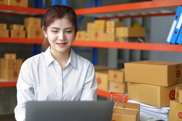 Small warehouse worker working with a laptop is checking the inventory. Entrepreneurs start-up e-commerce businesses working in the office.