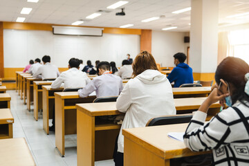 College students writing on final examination papers in the classroom concentrately