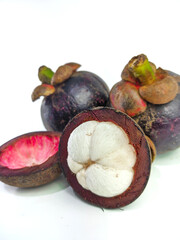 Mangosteen and cross section showing the thick purple skin and white flesh of the queen of friuts, on white background