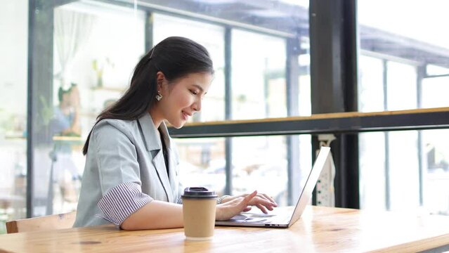 Happy smiling businesswoman working on laptop casually at coffee shop on vacation.