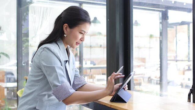 Attractive smiling happy business woman working on a tablet in a coffee shop cafe.