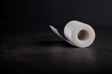 Small white thermal paper roll on black background