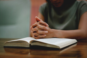 Religious concept. Belief. Close-up. A young woman praying thanks to the holy scriptures. God's...