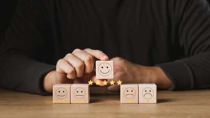 Customer satisfaction survey concept, customer hand selects wooden cube with smiley face icon, best service excellence rating for satisfaction.
