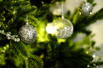 Evening Christmas atmosphere. Christmas balls of silver color hang on a Christmas tree
