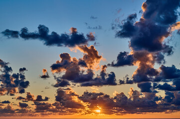 Sunset with dramatic clouds and blue sky over the sea 