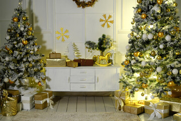 Christmas and New Year interior room with a high Christmas tree decorated with golden balls and a garland.