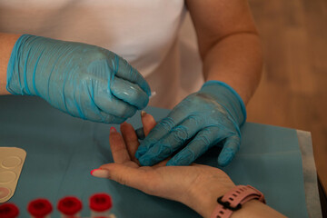 donor's day. a nurse in blue latex gloves takes a blood sample from a patient. medical blood jars....