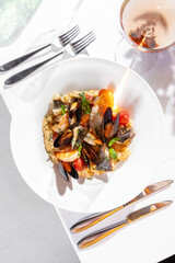 Fregola pasta with seafood and a glass of wine