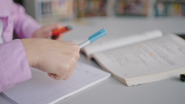 Girl does homework task writing in exercise book at desk