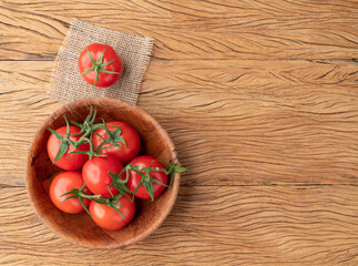 Red tomatoes on a bowl over wooden table with copy space
