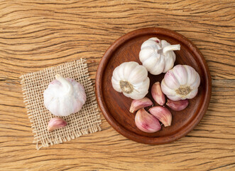 Garlic bulb and cloves on a plate over wooden table