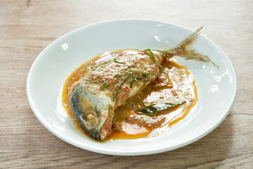 spicy boiled mackerel topping chop lemon grass in red curry sauce on plate
