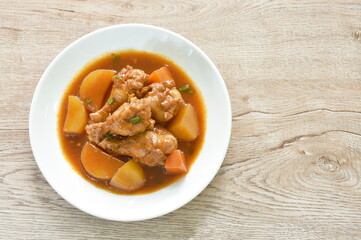 boiled chicken leg with potato in swet red gravy sauce stew on plate