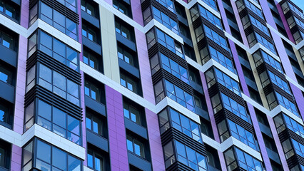 The facade of the building in purple,geometric patterns from windows and balconies, the colored wall of a modern multi-storey residential building, the abstract texture of the facade of the house
