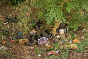 Disfigurement of sites wild landfill in the forest with plastic waste tires and packaging material