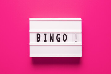 Lightbox with word bingo on pink background, top view. Bingo concept - lottery, casino, win game and jackpot