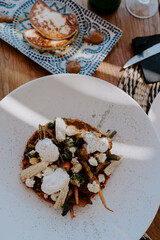Greek food served in a traditional Greek restaurant: greek salad, vegetables, greens, plates, beer
