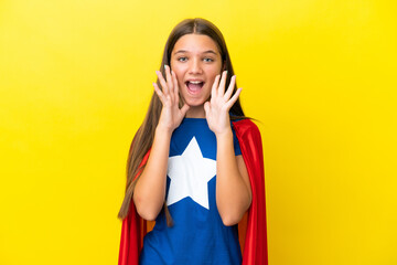 Little caucasian superhero girl isolated on yellow background shouting and announcing something